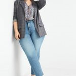 Stitch Fix model wearing plus-size clothing featuring floral blouse, grey plaid blazer, light wash jeans and white sneakers.