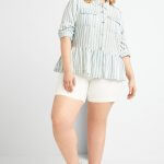 Stitch Fix model wearing plus-size clothing featuring blue and white chambray peplum shirt, white shorts and sneakers.