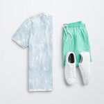 Stitch Fix Men’s outfit laydown featuring a blue and white tie-dye T-shirt, green shorts and white sneakers.