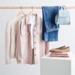 Stitch Fix women's petite with large bust outfit with jeans, backpack, shacket, top and sweater on rack and flats on books.