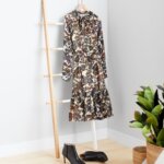 Stitch Fix women's petite with large bust outfit with floral print dress hanging on ladder next to black heel booties.