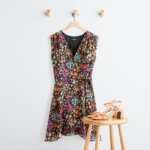 Stitch Fix women's petite with large bust outfit with black floral print dress hanging next to strappy heels on a stool.