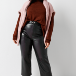 Stich Fix Women’s model wearing a cozy fall aesthetic outfit with leather pants, burgundy turtleneck, pink sweater and white mules.