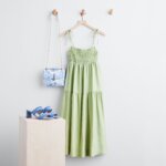 Stitch Fix Bridgerton inspired women’s outfit featuring green tiered maxi dress, blue sandals and white and blue purse.