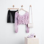 Stitch Fix women's edgy leather skirt outfit with black mini skirt, light purple lace long-sleeve top, white crossbody bag and light purple heels.