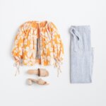 Stitch Fix women's picnic outfit featuring orange and white floral jacket over tank top, blue pants and brown sandals.