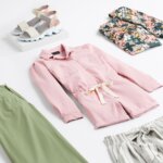 Stitch Fix women’s road trip outfit with pink romper, green pants, floral top, striped shorts and multicolored sandals.