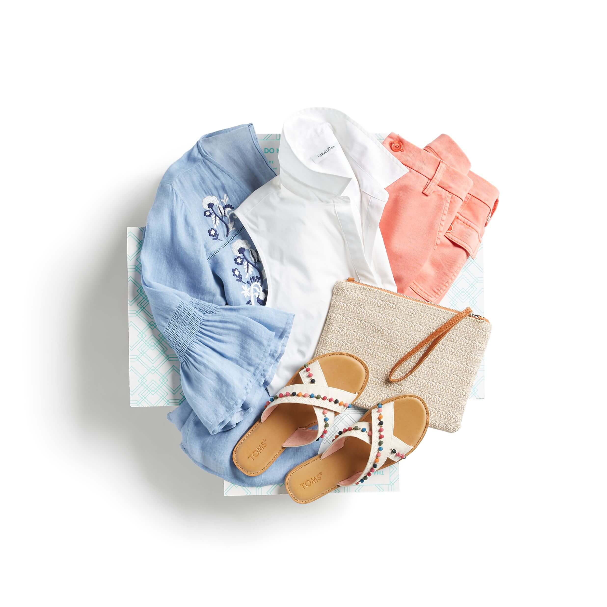 Stitch Fix Women’s outfit featuring coral jeans, blue embroidered blouse, white button-down, embroidered sandals and straw clutch.