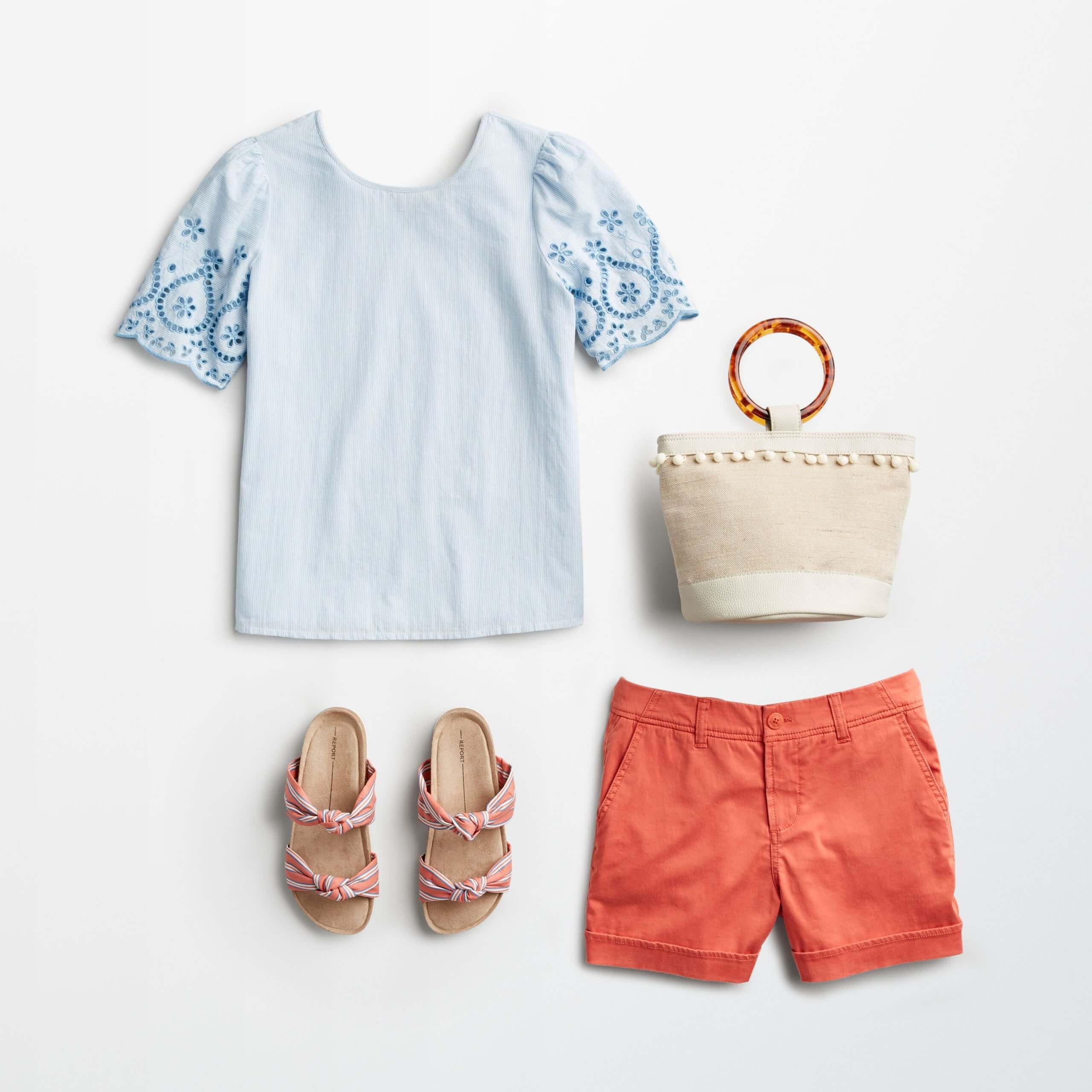 Stitch Fix women's 4th of July outfit laydown featuring a blue embroidered top, red shorts, white woven bag and red and white striped sandals.