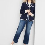 Stitch Fix women's model wearing preppy style outfit featuring navy and white blazer over white shirt, blue jeans and white loafers.