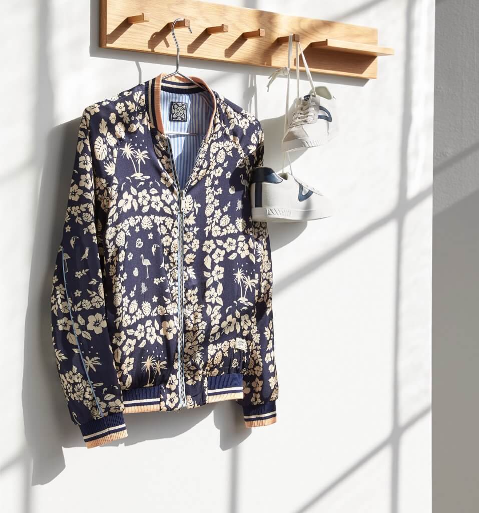 Stitch Fix women’s navy jacket with beige and orange tropical pattern hanging next to a pair of white and navy sneakers.