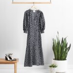 Stitch Fix maxi dress in black with white abstract floral print and balloon-sleeves next to black heels and potted plants.