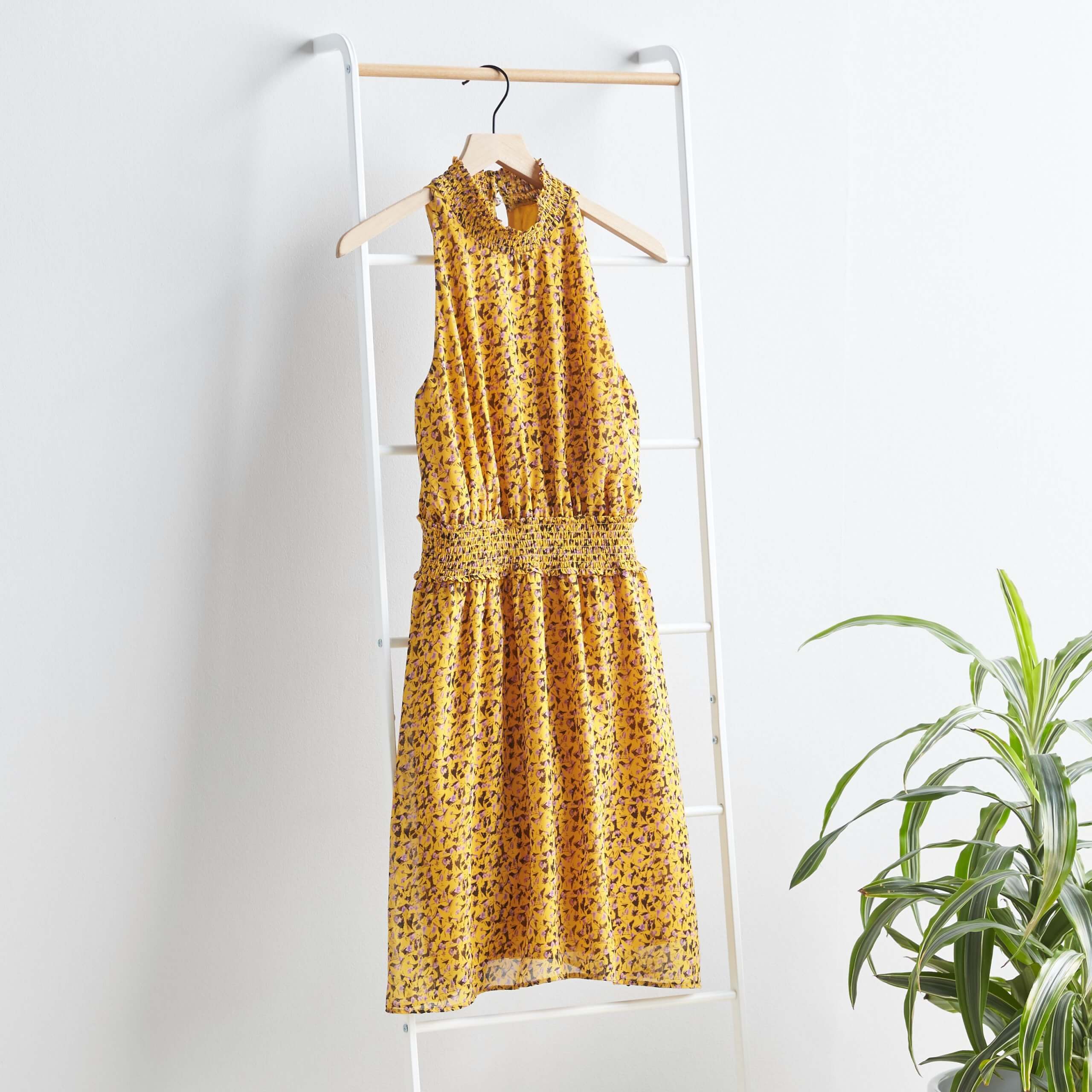Stitch Fix women’s mustard sleeveless dress hanging on a ladder next to a plant.