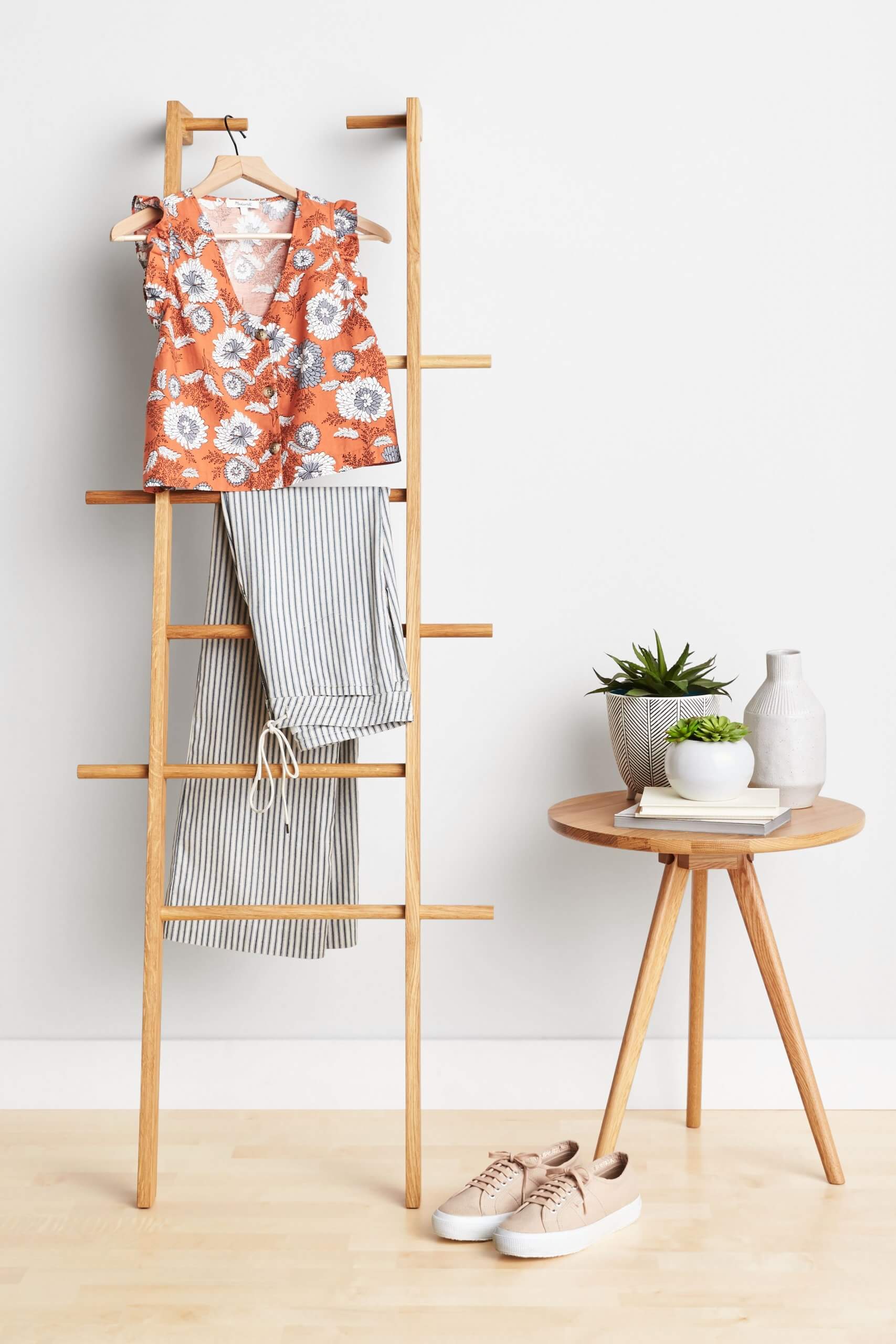 Stitch Fix women’s orange and blue floral blouse with striped pants on ladder next to table with vases and tan sneakers.