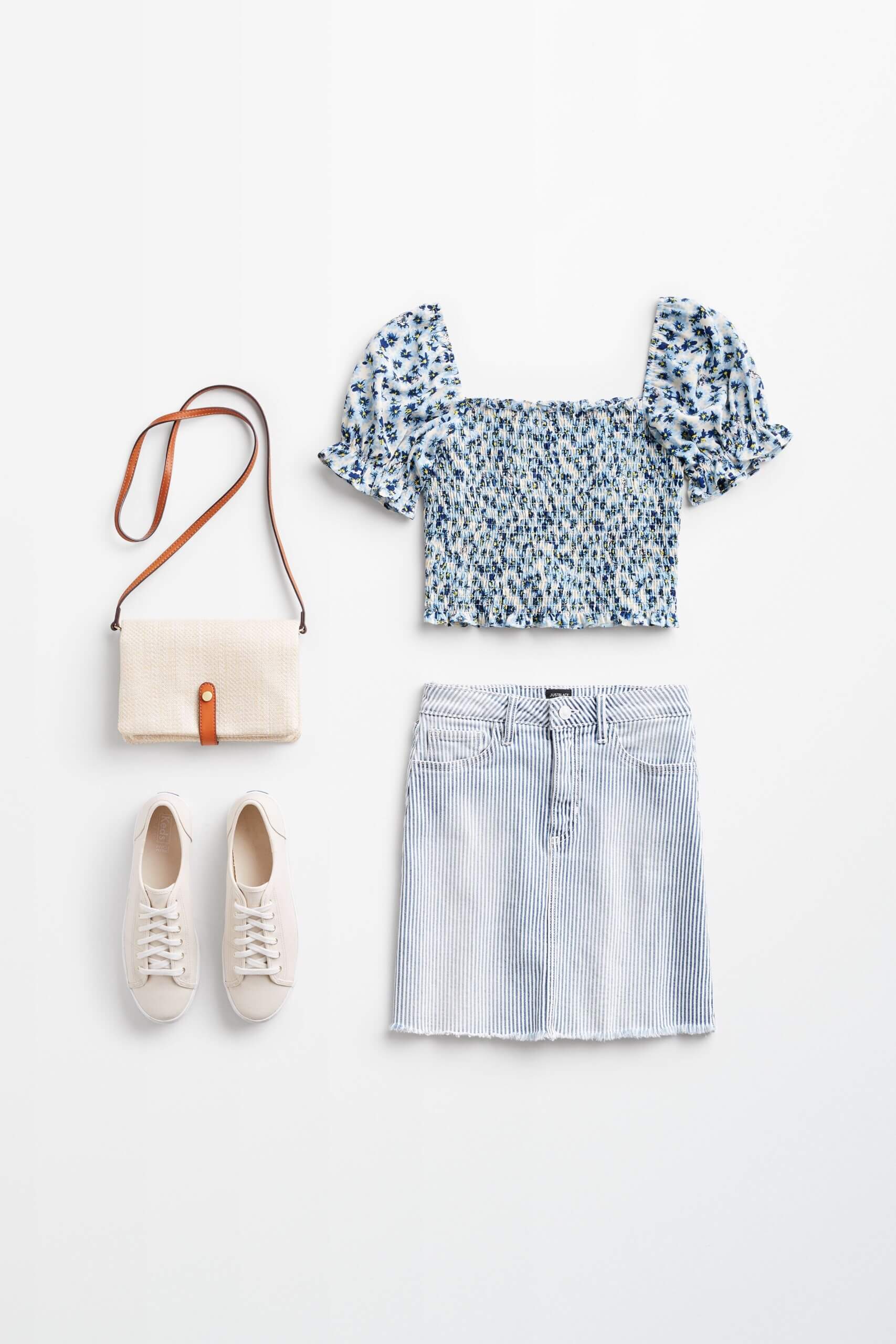 Stitch Fix Women’s outfit laydown featuring denim skirt, smocked blouse with puff sleeves, sneakers and crossbody bag.
