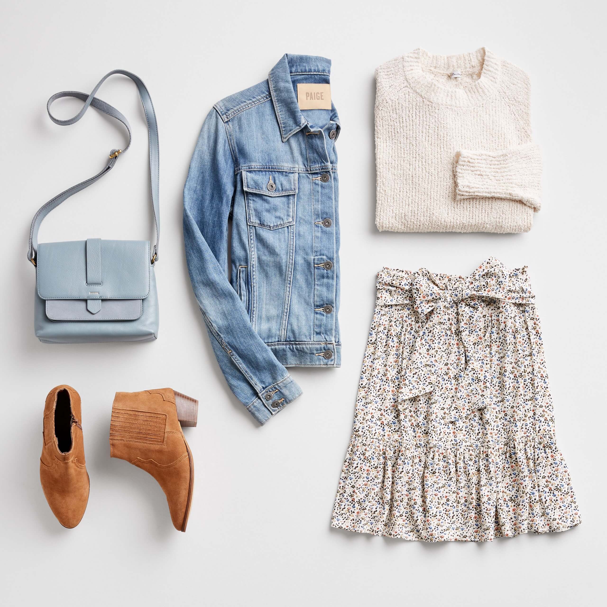 Stitch Fix women’s jean jacket outfit laydown with light blue crossbody bag, blue denim jacket, off-white knit crewneck sweater, brown heeled booties and white and blue micro floral skirt with a bow belt.