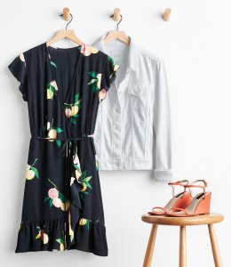 Stitch Fix women’s accessories to wear with black dress featuring white denim jacket on hanger, coral wedge heels on stool with black floral print wrap dress with tie-waist and ruffle hem on hanger.