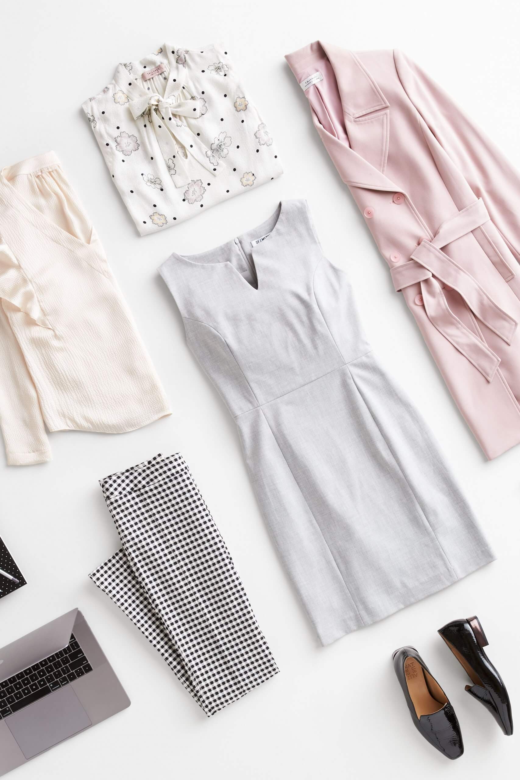 Stitch Fix Women’s outfit laydown featuring pink trench jacket, white patterned tie-neck blouse, cream blouse, black and white checkered pants, grey sheath dress and black loafers.
