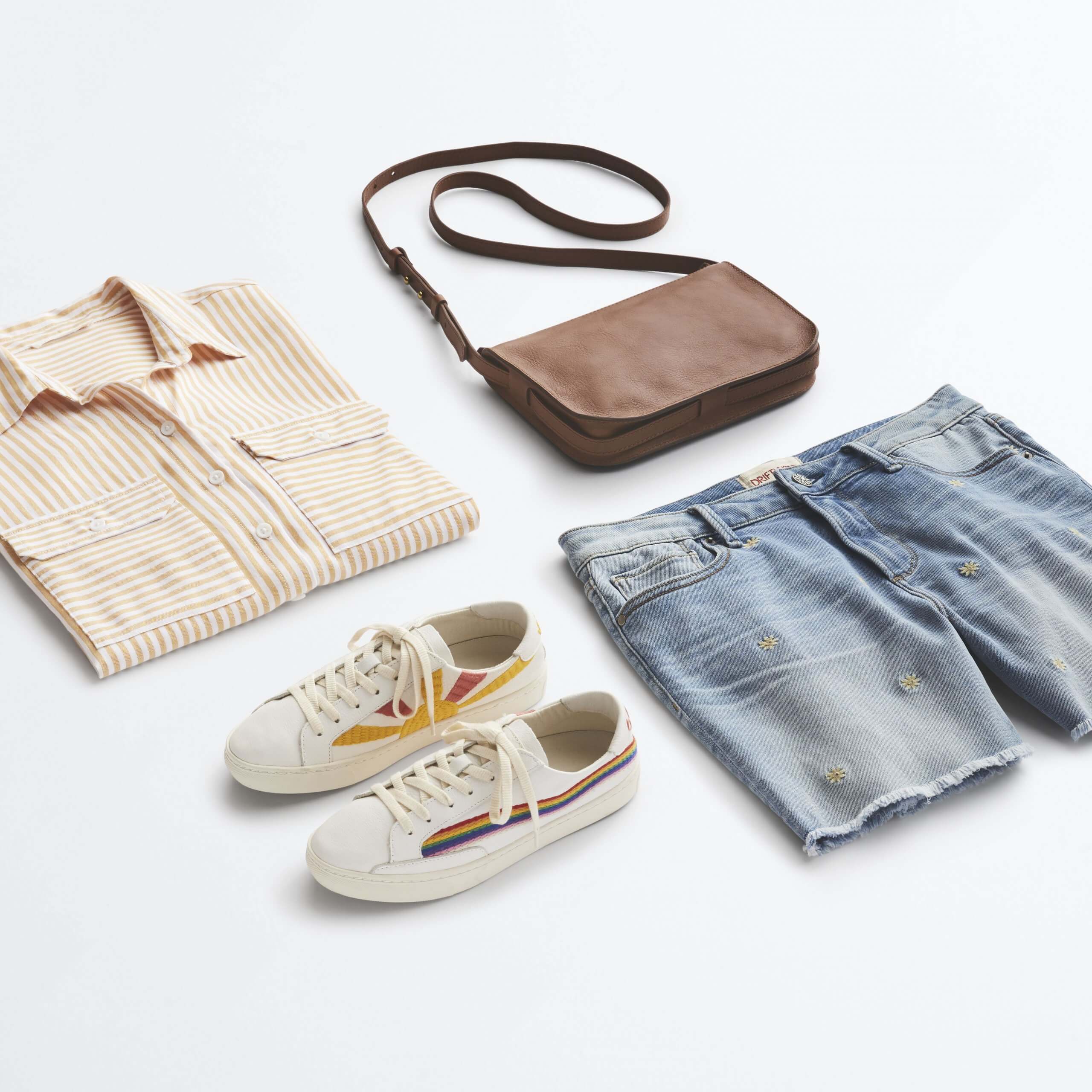 Stitch Fix Women's outfit laydown featuring cream striped button-down shirt, cut-off denim shorts, white sneakers with rainbow stripe and brown crossbody bag. 