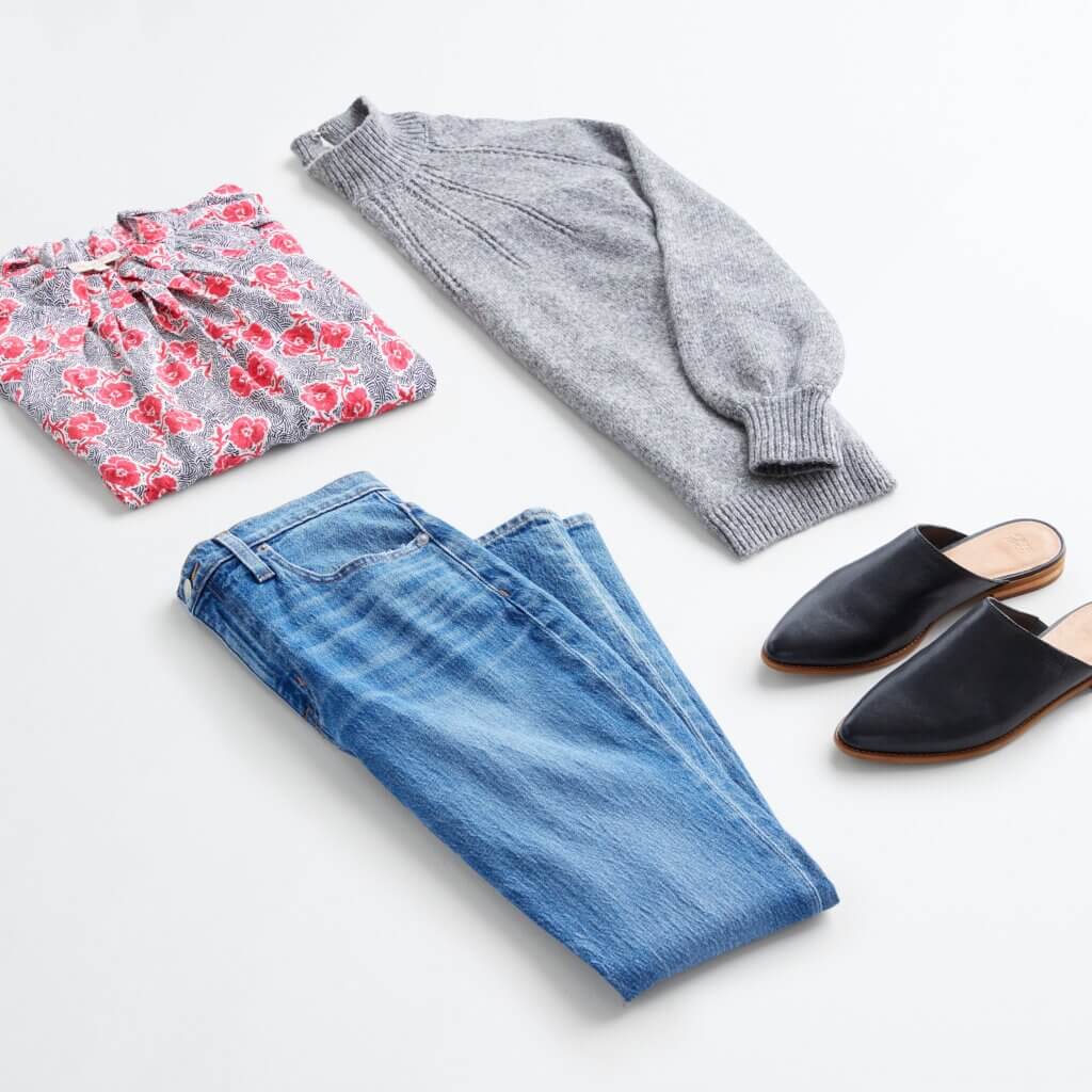 Stitch Fix women’s business casual outfit with blue jeans, grey pullover sweater, grey, red and white floral blouse and black slides.