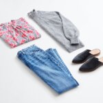 Stitch Fix women’s business casual outfit with blue jeans, grey pullover sweater, grey, red and white floral blouse and black slides.