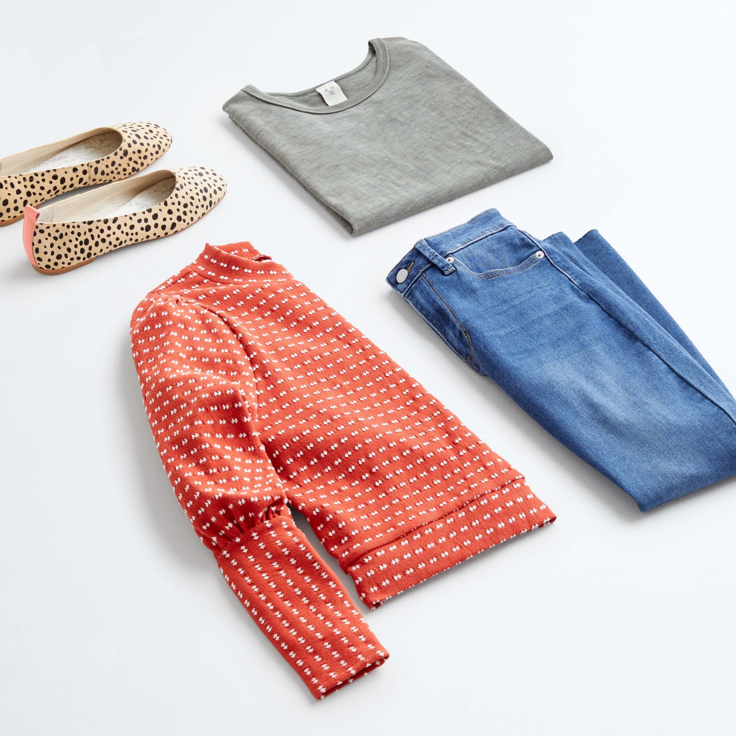 Stitch Fix women’s outfit laydown showing how to mix prints and patterns featuring gray shirt, blue jeans, leopard print flats and orange polka dot sweatshirt.
