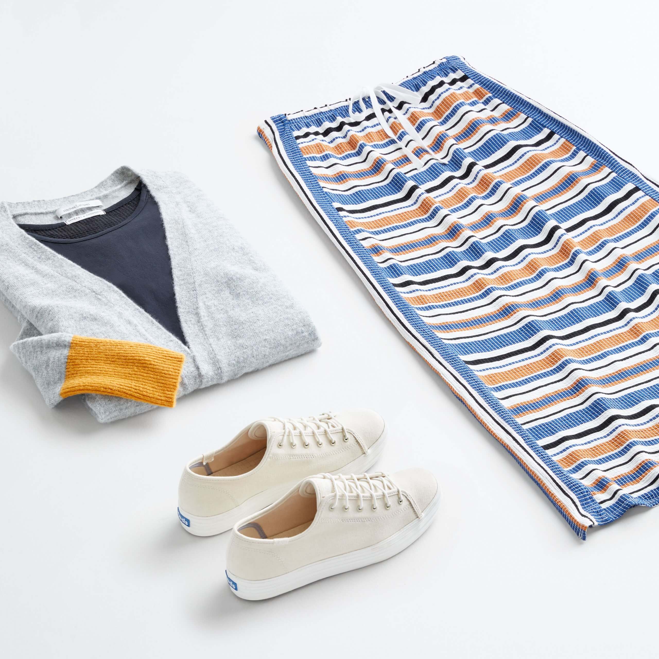 Stitch Fix women’s outfit laydown featuring off-white sneakers, navy shirt under grey and yellow cardigan sweater and striped maxi skirt.