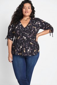 Stitch Fix model wearing plus-size clothing featuring black floral wrap blouse with tie-sleeve details and blue jeans.
