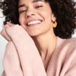 Stitch Fix women’s model wearing thick gold hoop earrings and blush pink sweater.