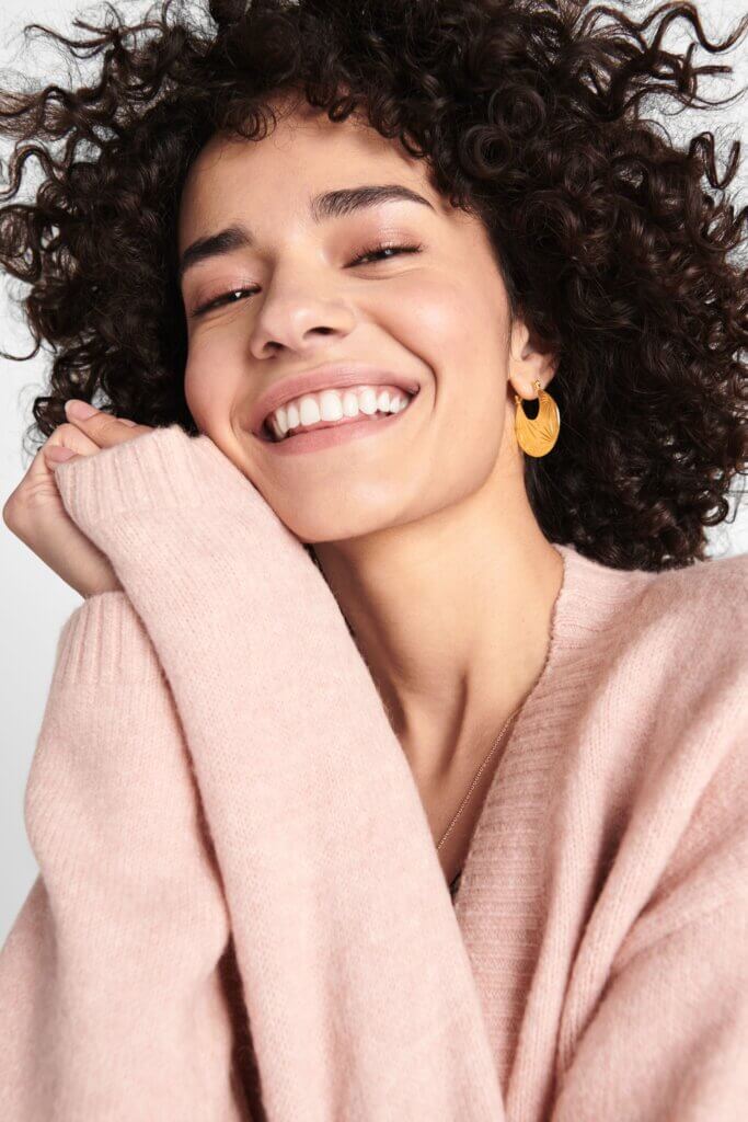 Stitch Fix women’s model wearing thick gold hoop earrings and blush pink sweater.