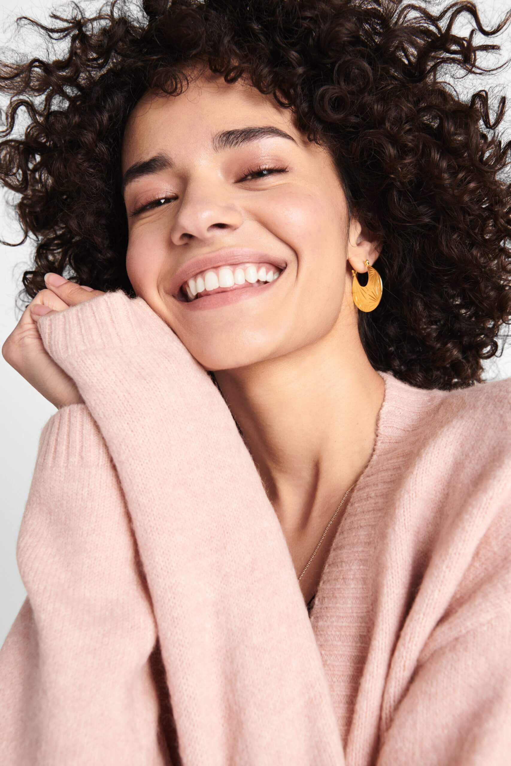 Stitch Fix women’s model wearing thick gold hoop earrings and blush pink sweater.