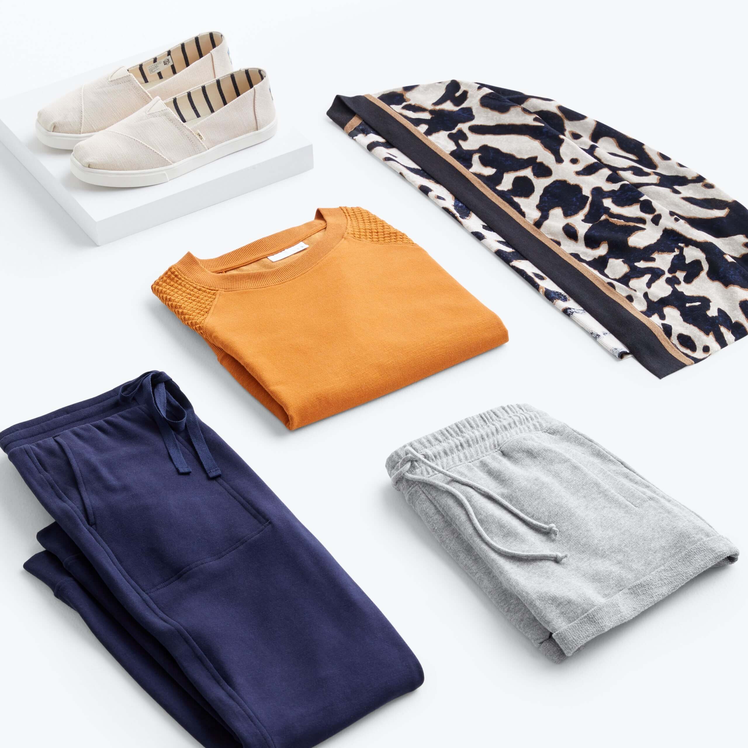 Stitch Fix women’s workleisure outfit with navy pants, grey shorts, orange pullover, black and beige abstract print cardigan and beige slip-on sneakers.