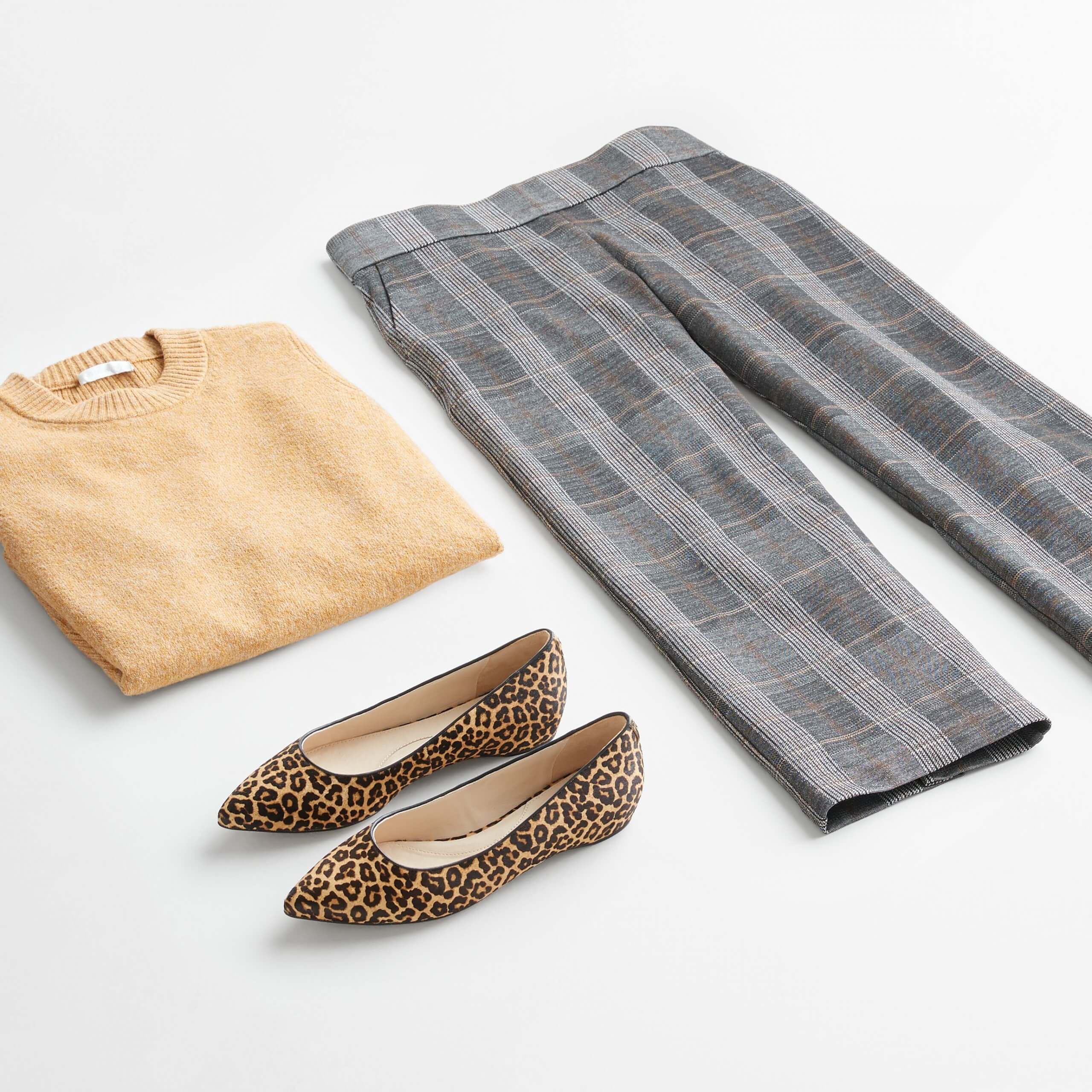 Stitch Fix Women’s outfit laydown featuring grey wide-leg pants, camel crew neck pullover and brown animal-print flats. 