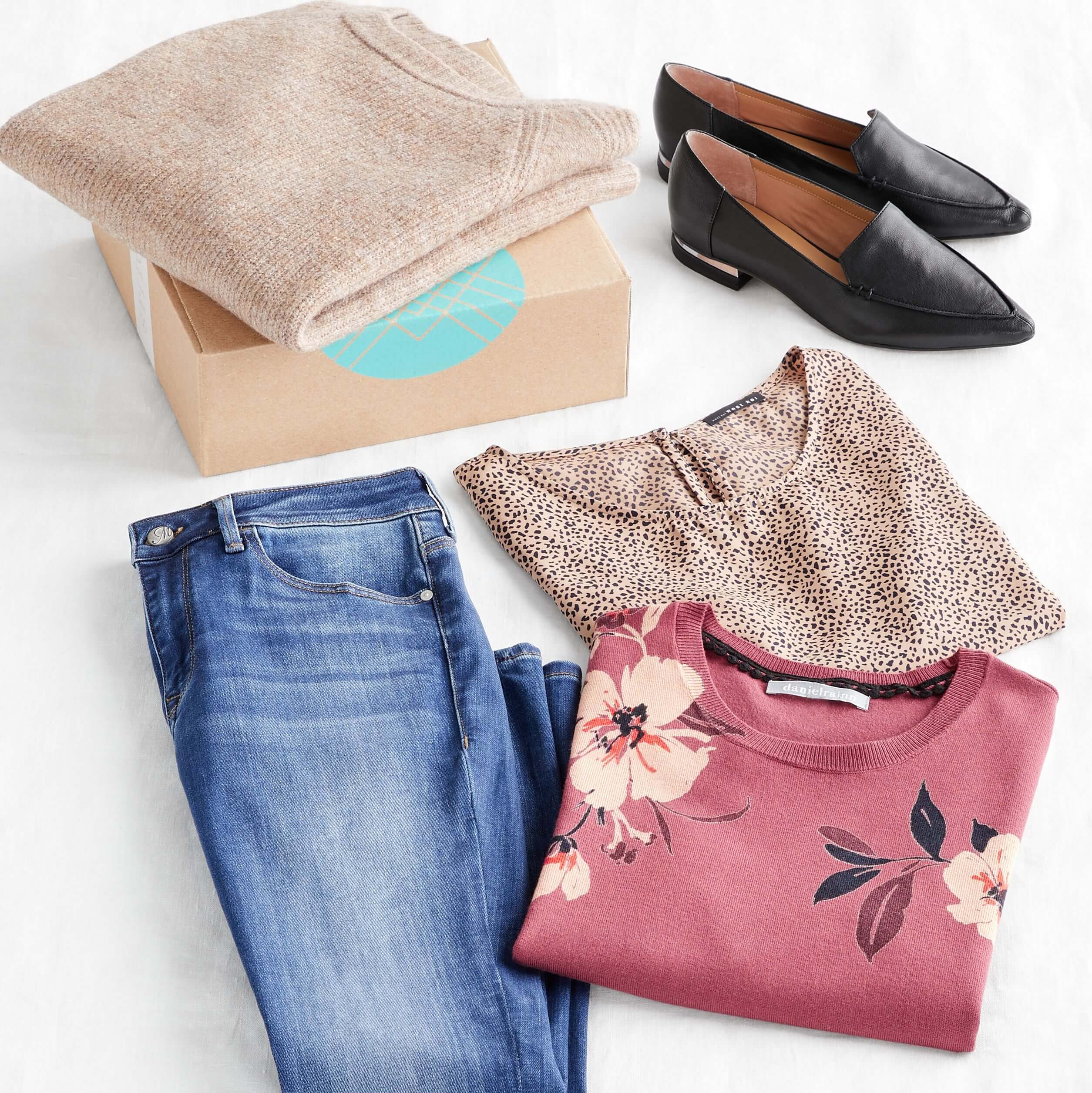 Stitch Fix Women's outfit laydown featuring a tan pullover on a Stitch Fix delivery box next to black loafers, blue jeans, brown animal-print shirt and pink floral pullover.