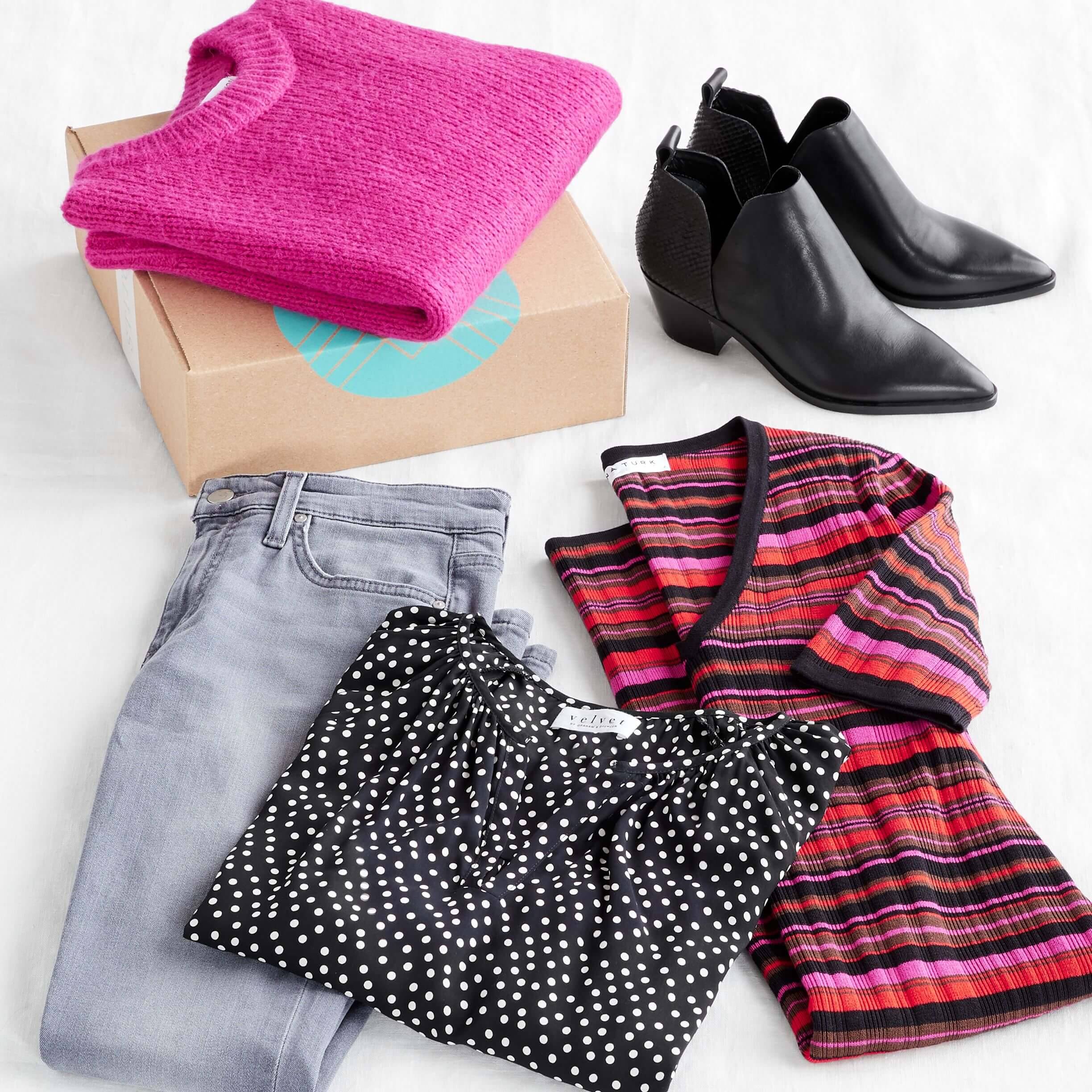 Stitch Fix Women’s outfit laydown featuring a bright pink crew neck sweater on a Stitch Fix delivery box, next to black booties, pink striped sweater dress, black polka dot top and grey jeans. 