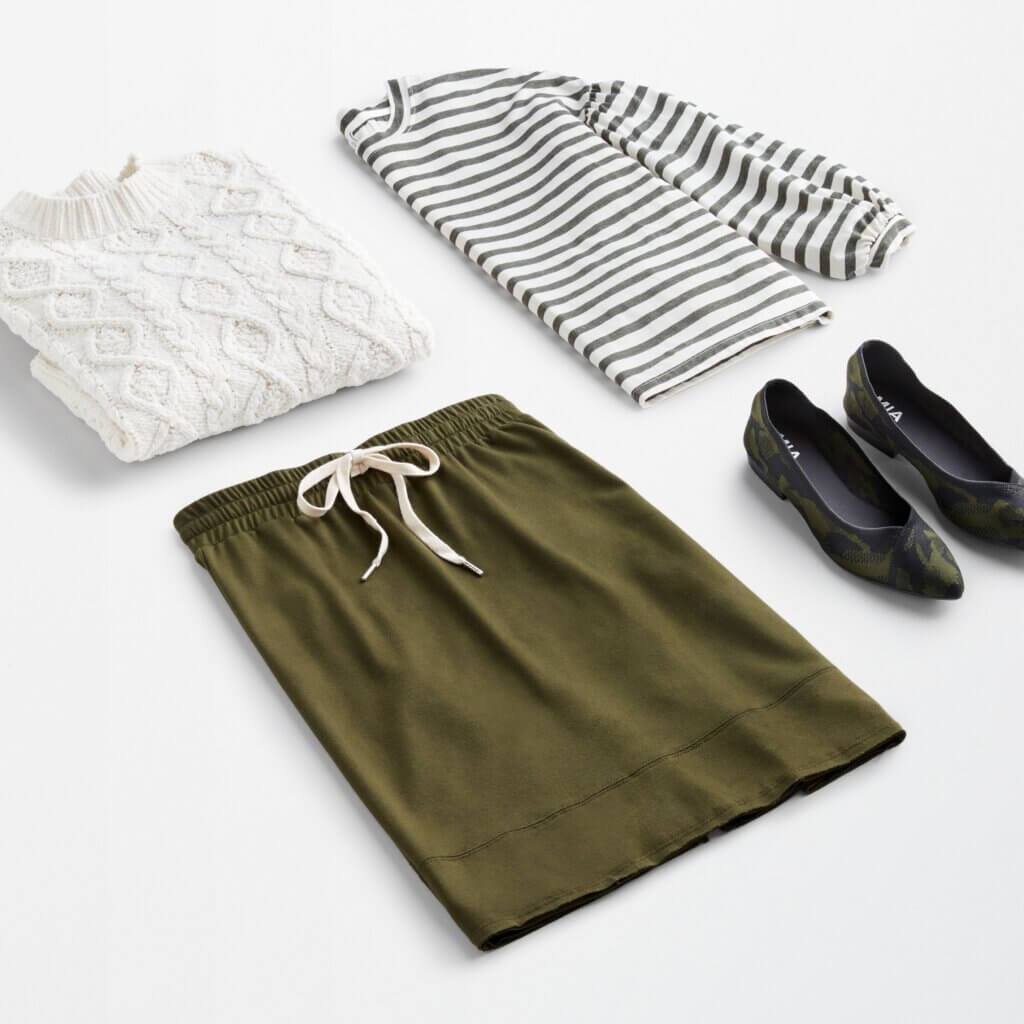 Stitch Fix women’s workleisure outfit with white cable-knit sweater, grey and white striped top, olive knit skirt and printed flats.