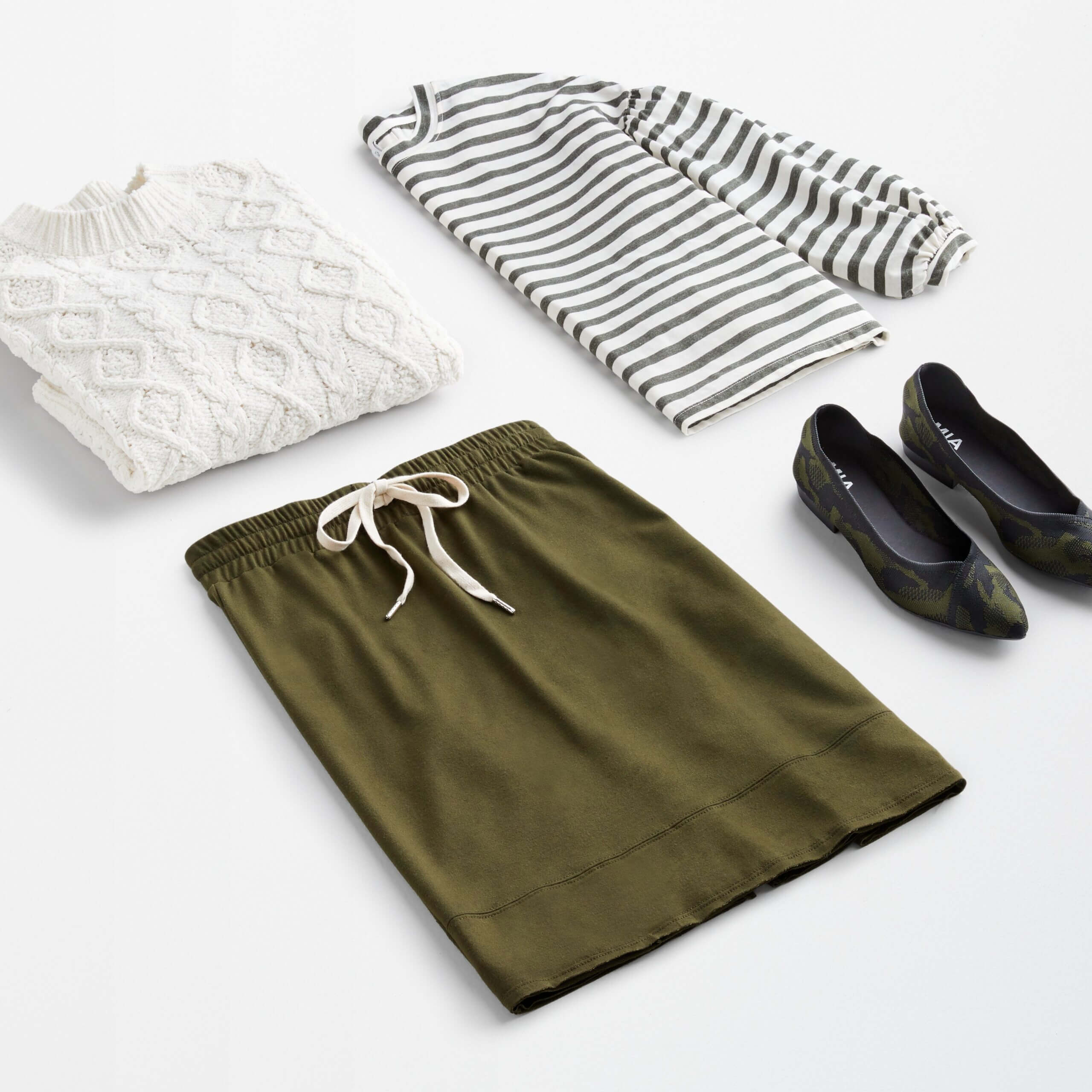 Stitch Fix women’s workleisure outfit with white cable-knit sweater, grey and white striped top, olive knit skirt and printed flats.