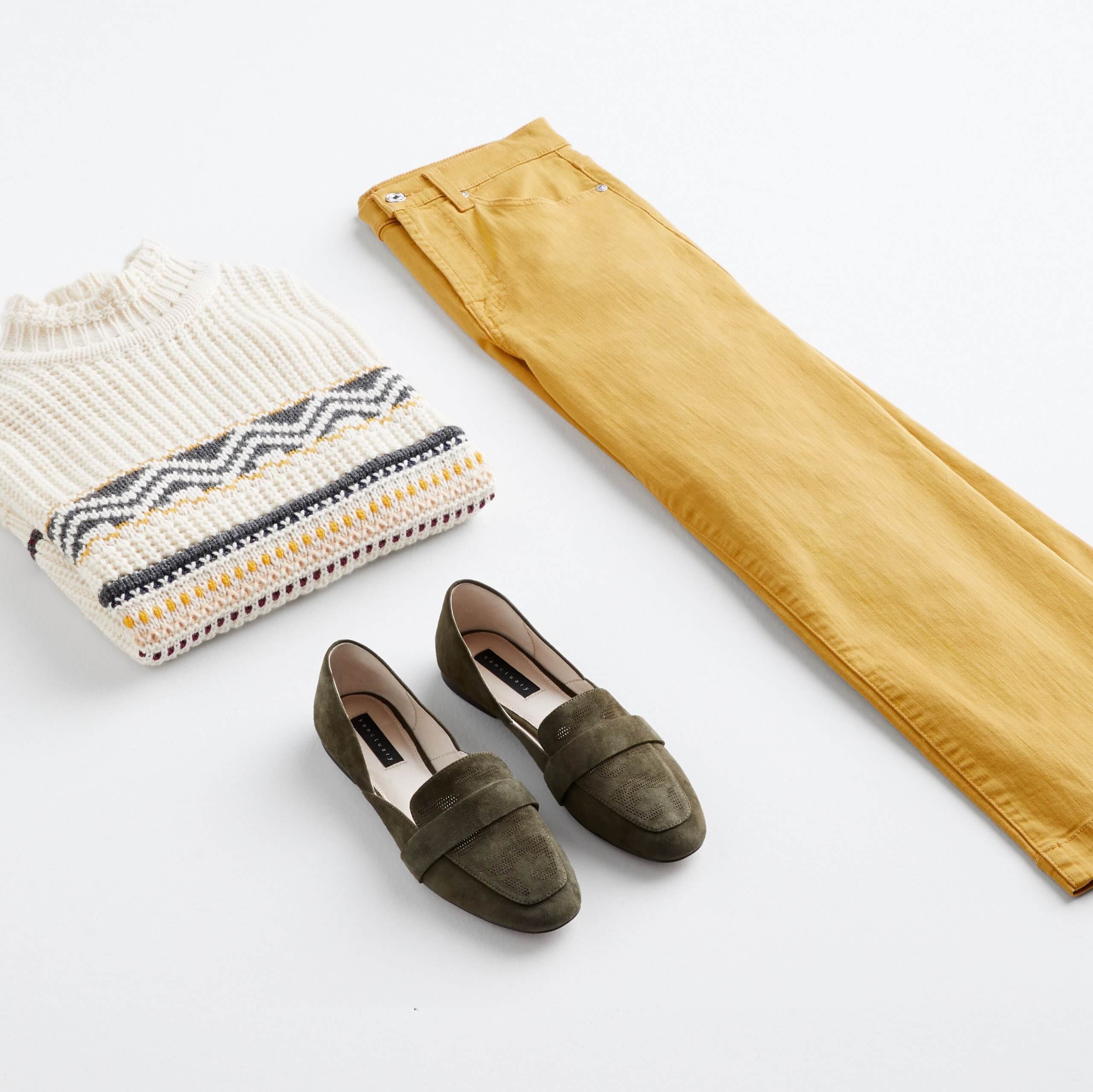 Stitch Fix Women’s outfit laydown featuring mustard wide-leg jeans, cream mock neck sweater and dark green loafers. 