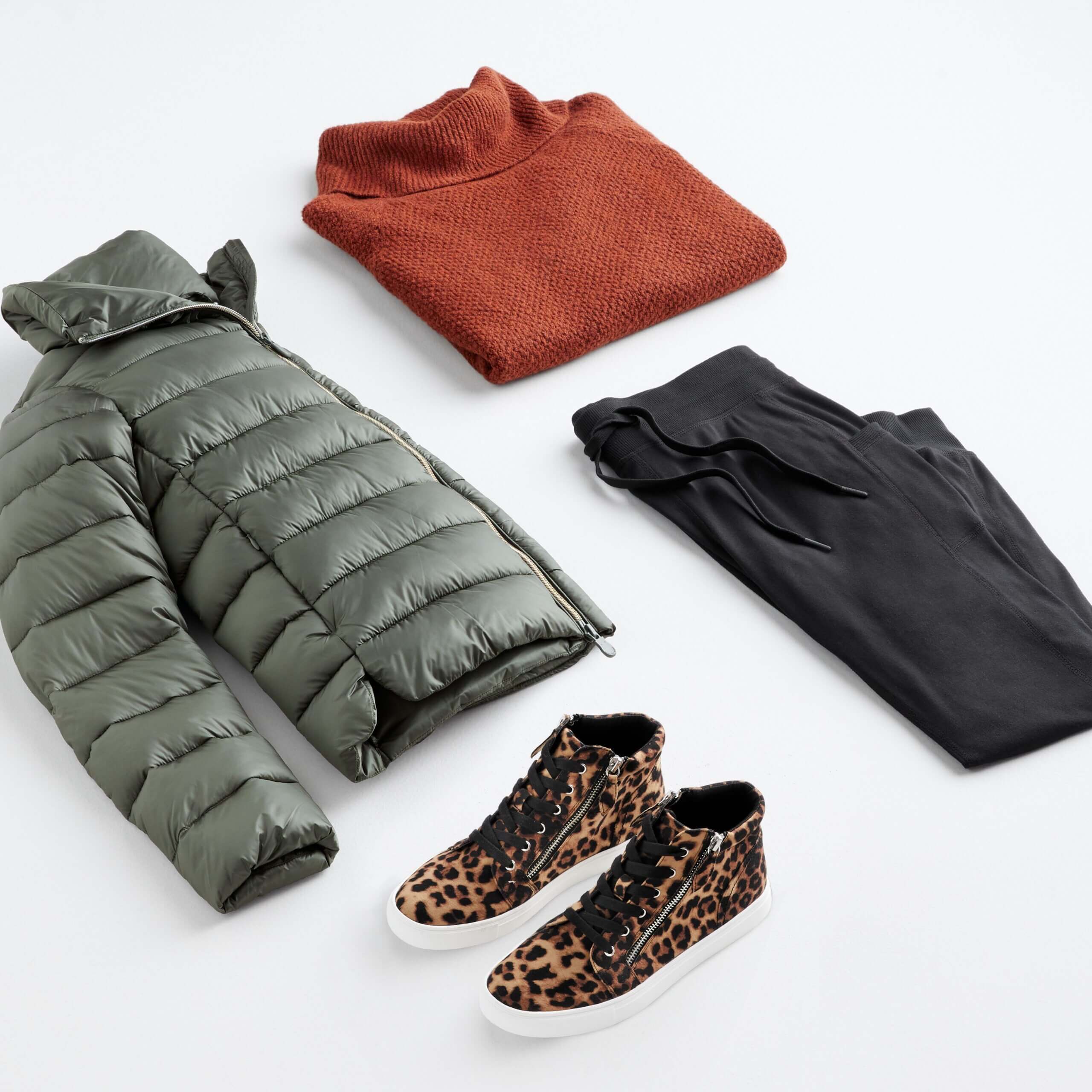 Stitch Fix Women's outfit laydown featuring green puffer jacket, burnt orange turtleneck pullover sweater, black jogger pants and cheetah-print high top sneakers. 