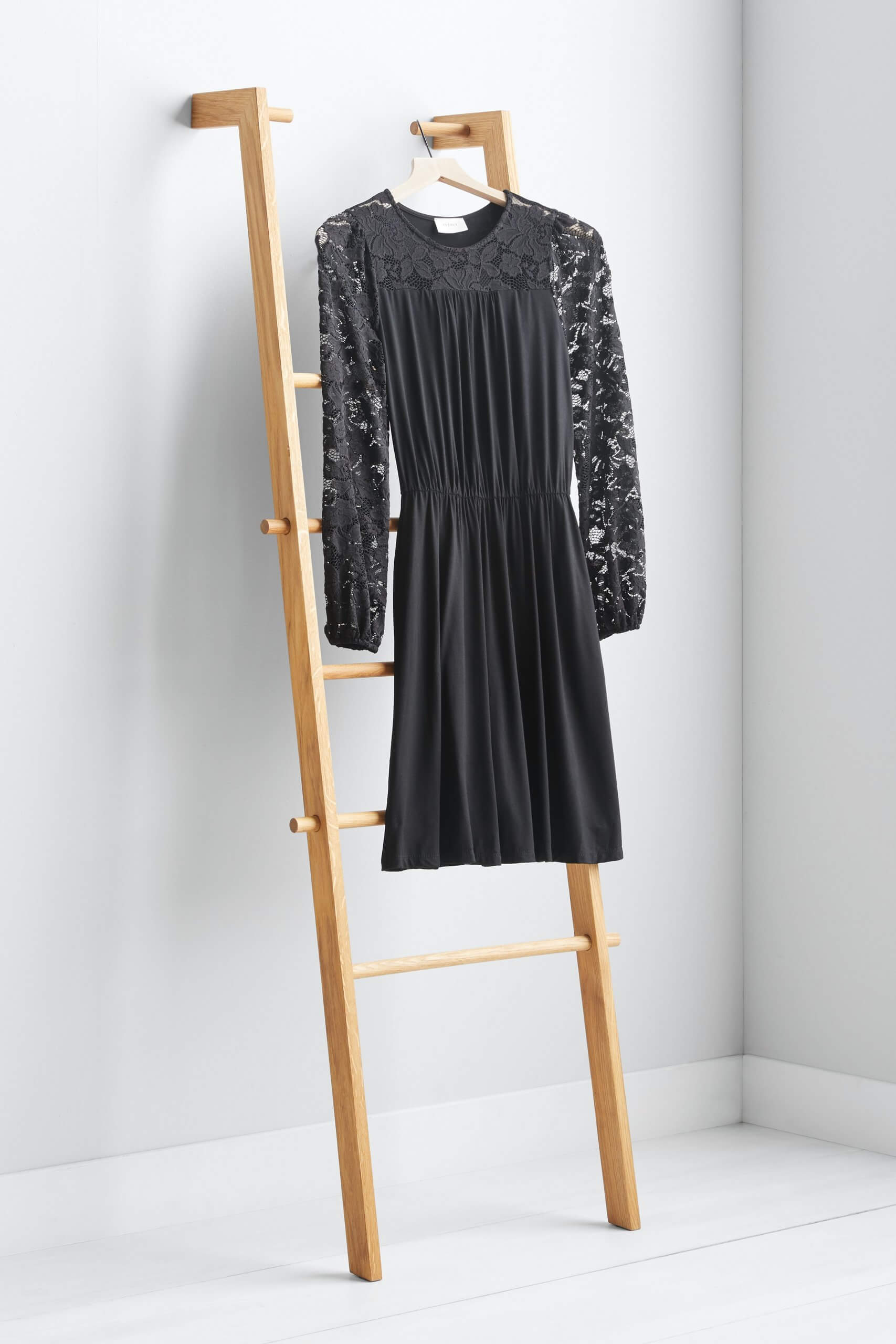 Stitch Fix women’s black dress with lace sleeves hanging on a wooden ladder.