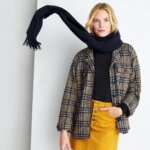 Stitch Fix model wearing black scarf with women’s plaid shacket, black sweater and mustard button-closure denim skirt.