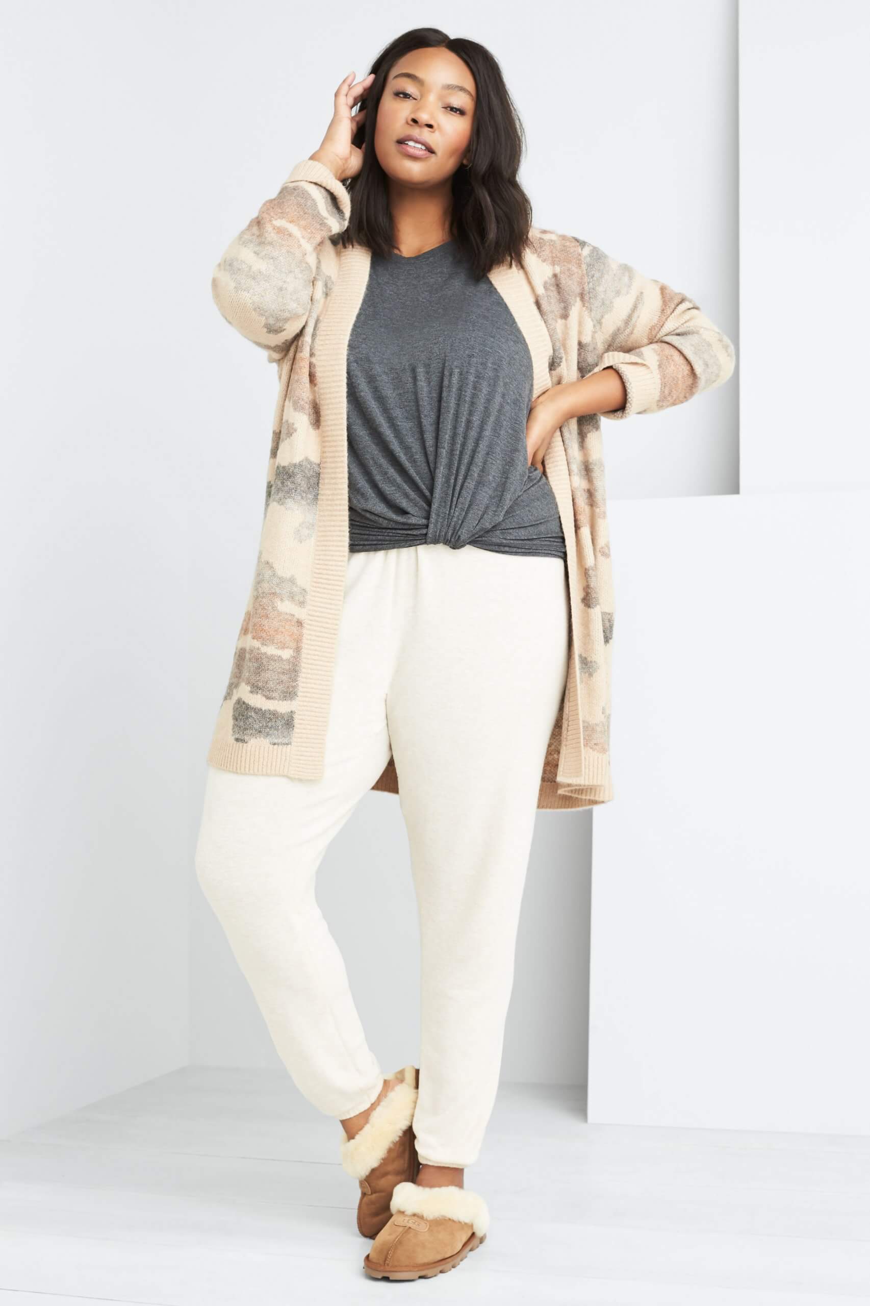 Stitch Fix model wearing plus-size clothing featuring grey knot front t-shirt, tan printed cardigan, cream joggers and slippers