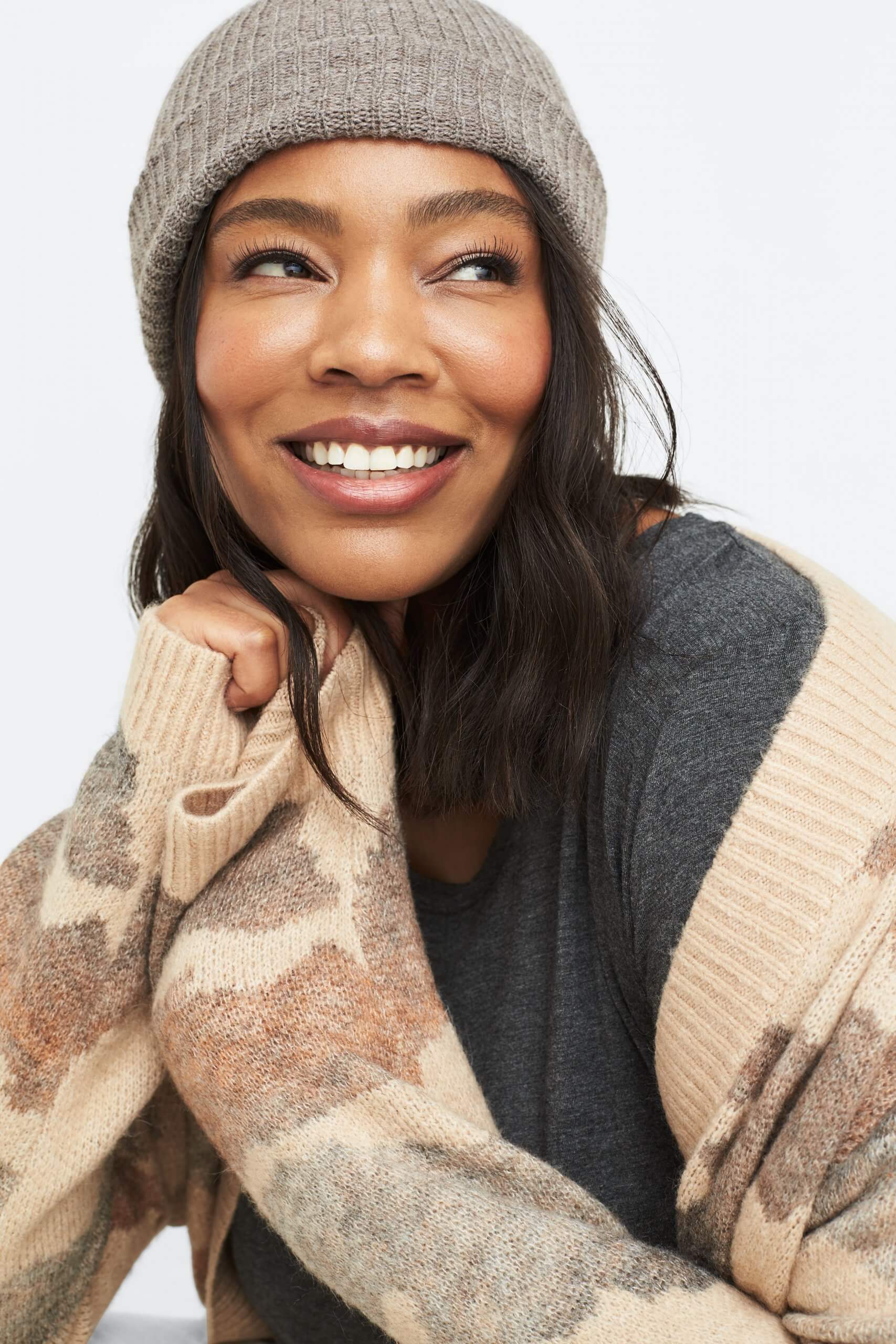 Stitch Fix Women’s model wearing a grey beanie, grey knit top and tan printed cardigan. 