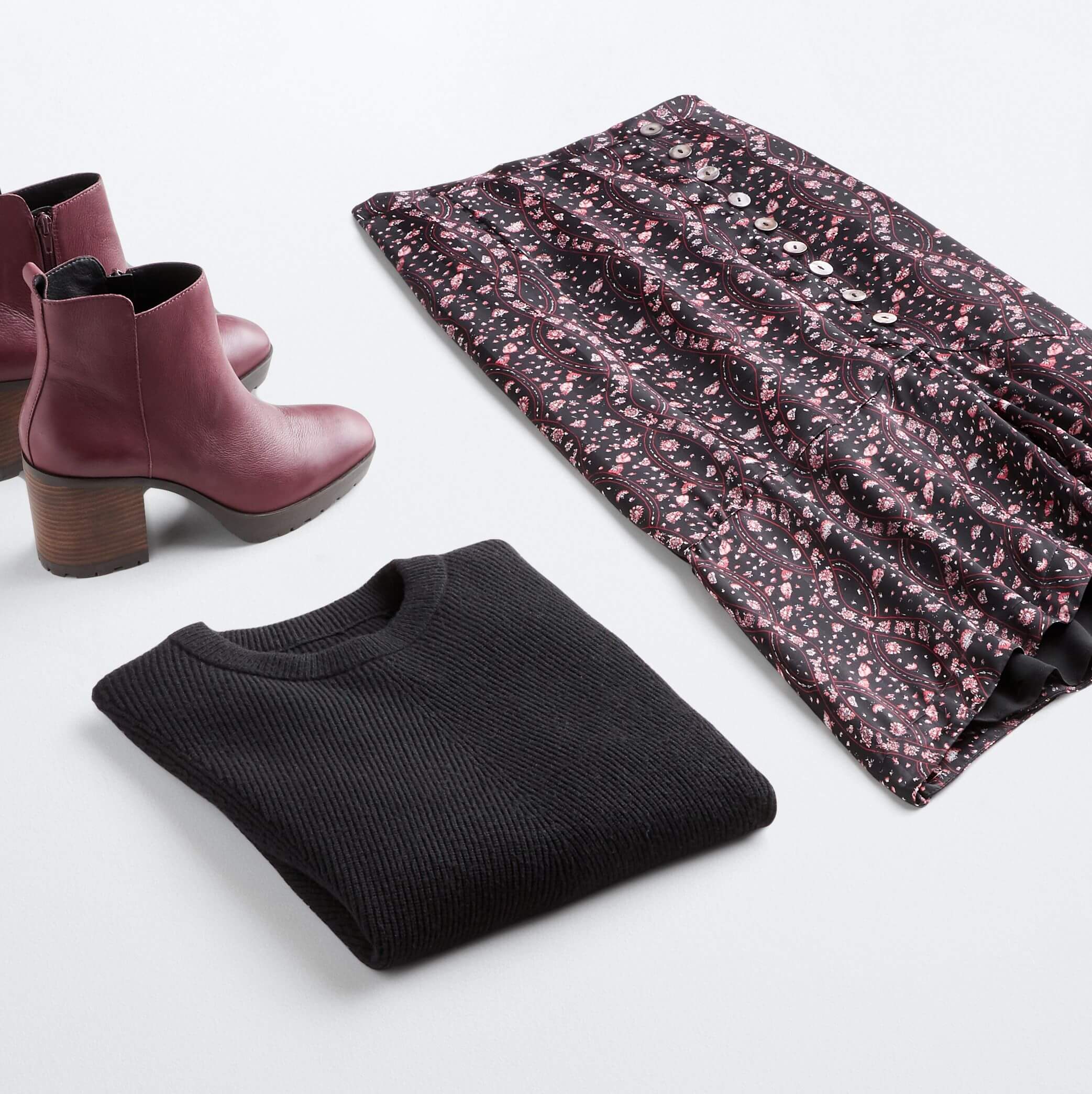 Stitch Fix Women's outfit laydown featuring purple floral skirt, black pullover sweater and purple heeled booties. 