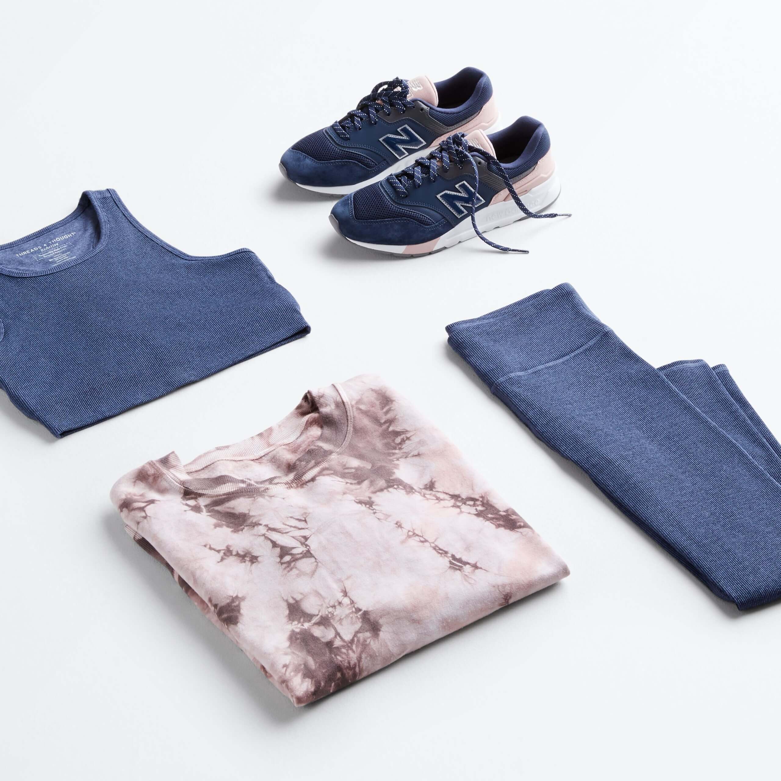 Stitch Fix women’s outfit featuring matching blue sports bra and legging set, brown tie-dye pullover sweater and navy, pink and white tennis shoes.