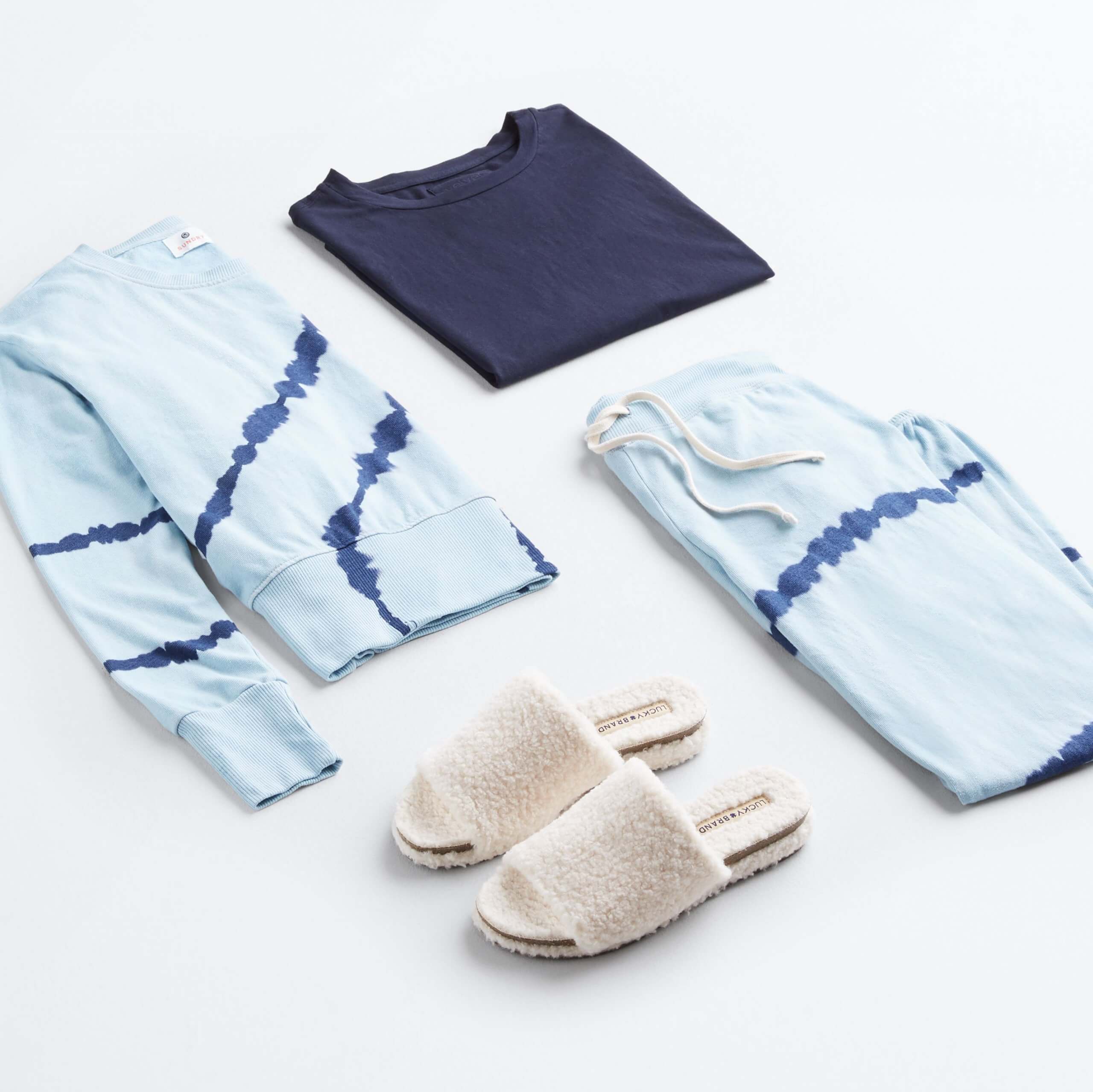 Stitch Fix women’s 4th of July outfit laydown featuring blue tie dye sweatshirt, blue tie dye sweatpants, navy blue shirt and white slippers.
