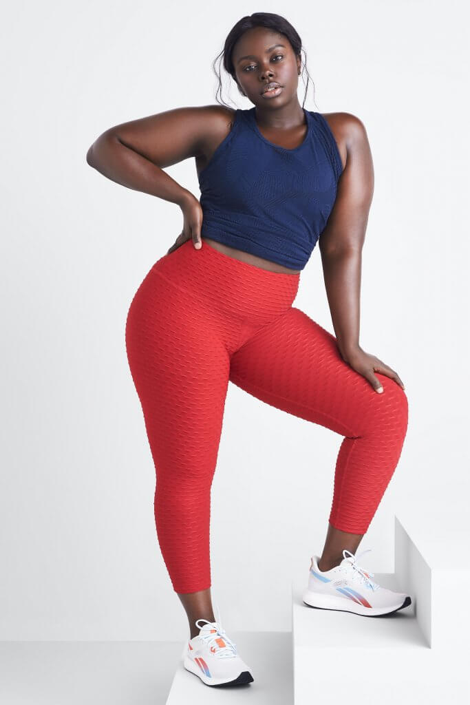 Stitch Fix women’s model wearing plus-size navy cropped tank, red textured leggings and red and blue accented white sneakers.