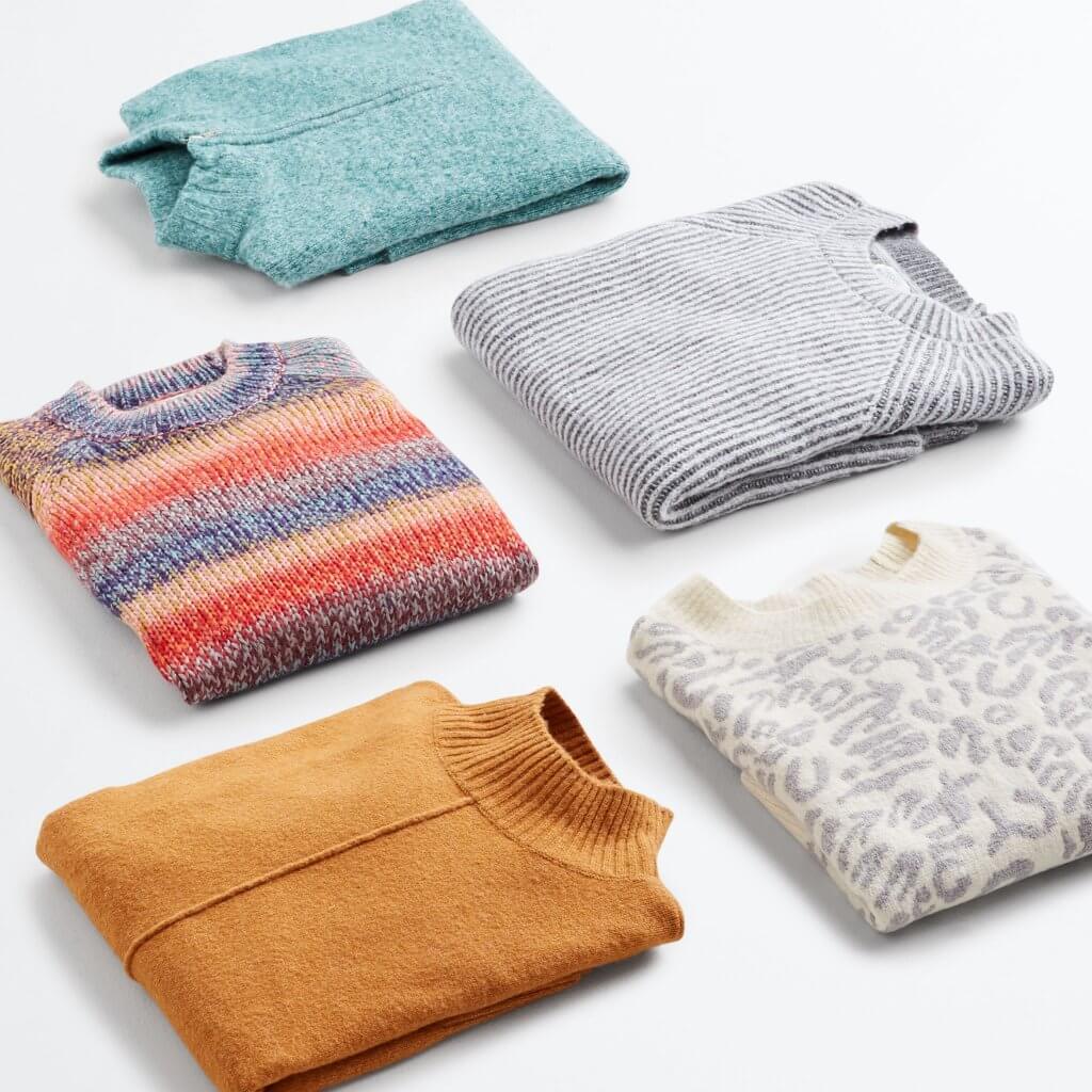 Stitch Fix women’s lay down of sweaters featuring a mustard mockneck, multicolor crew, teal quarter-zip, grey crew and leopard-print.