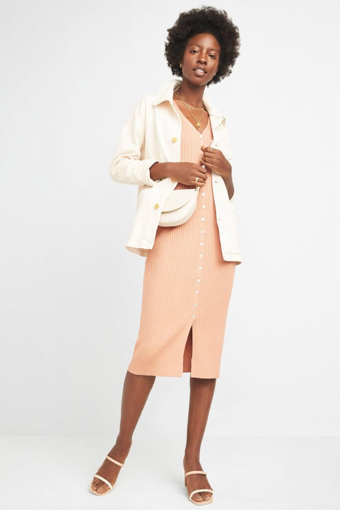 Stitch Fix women’s model in chic style outfit featuring peach midi-dress, off-white collared jacket, off-white crossbody bag and white sandals.