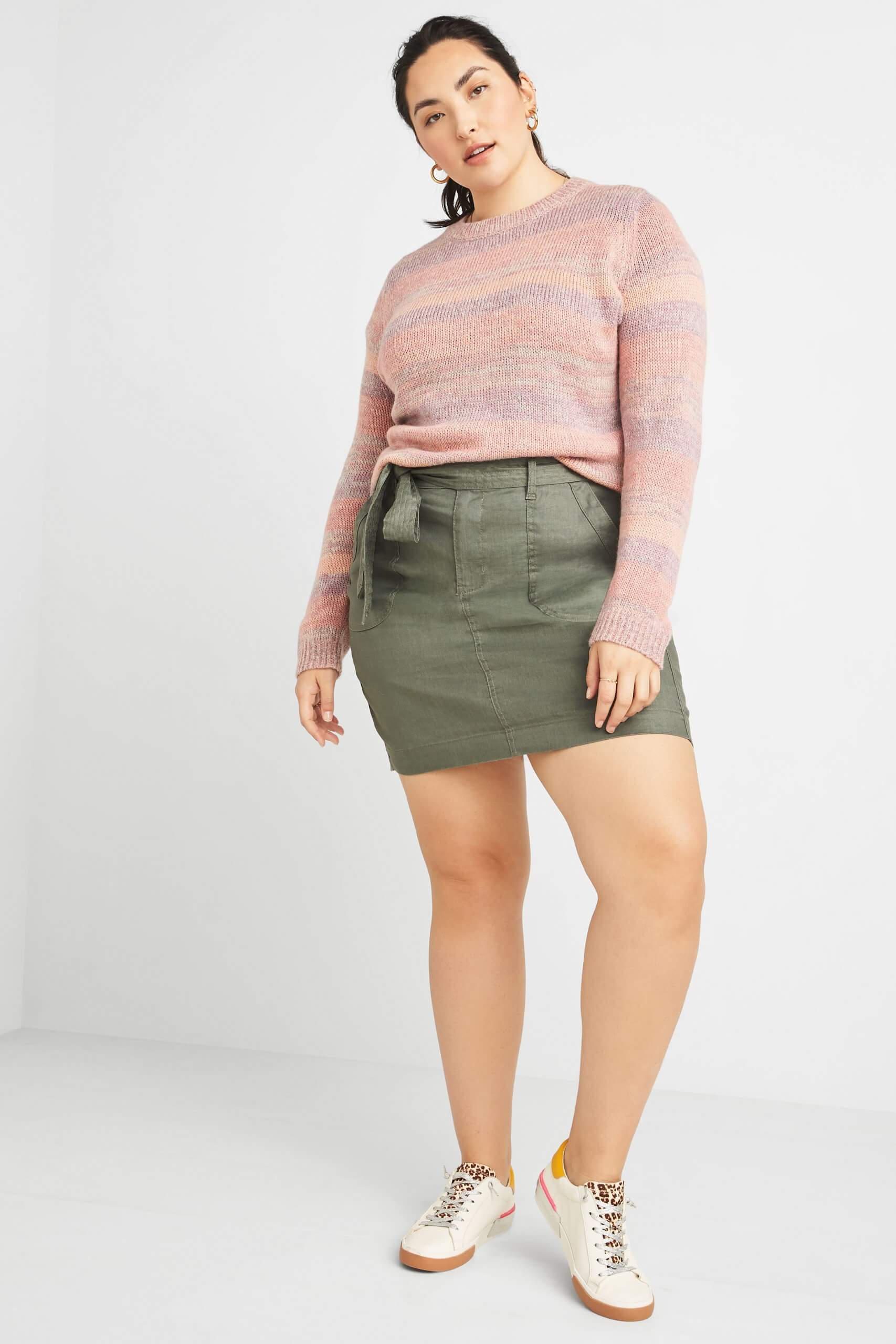 Stitch Fix model wearing plus-size eco-friendly pink sweater, olive utility skirt and off-white sneakers.